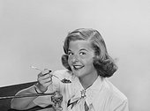 Young woman holding fork of beans, smiling, portrait