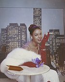 Woman wearing feather boa sitting with cigarette in hand, portrait