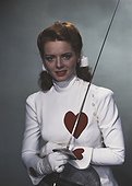 Young woman in fencing costume holding sword, smiling, portrait