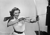 Young woman aiming arrow, smiling