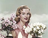 Young woman standing beside flowers, portrait