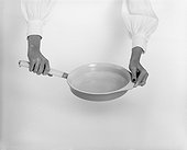Woman holding pan against white background, close-up