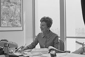 Senior woman sitting at desk writing on notepad, smiling