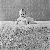 Baby boy crawling on rug, smiling