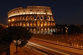 Rome, Italy.. The colosseum lit up at night with cars blurring past.