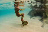 A woman on the sandy bottom of the ocean wearing a red and yellow mermaid costume.. British Virgin Islands.