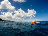 A woman in a blue bathing suit, goggles and orange swim cap smailes as she treads waterr.. British Virgin Islands.
