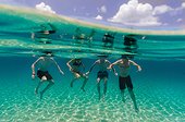 Three men and a woman tread water in the ocean.. San Salvador, Bahamas.