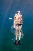 A man in a black bathing suit, a pink dive mask and fins swims toward the surface of the water.. British Virgin Islands.