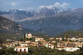 Peloponnese, Greece.. The Taygetos mountains loom behind a church in a village in the Peloponnese.