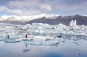 Jokulsarlon, Iceland. A woman on an inflatable paddleboard paddling on the Jokulsarlon glacier lagoon.