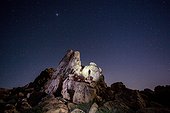 Joshua Tree National Park, California. A man climbing rocks in Joshua Tree National Park at night.