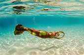 A woman in the water wearing a red and yellow mermaid costume.. British Virgin Islands.