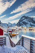 Norway, Nordland, Lofoten Islands, Scandinavia, Moskenesøya, Traditional village of Reine in Lofoten Islands with its typical fishermen houses called Rorbuer on a winter morning with the mountains in the background covered with snow