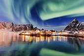 Norway, Nordland, Lofoten Islands, Scandinavia, Moskenesøya, The northern lights in the sky above Sakrisoy village in Lofoten islands on a winter night with the mountains covered with snow