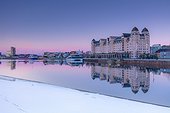 Norway, Oslo county, Oslo, Scandinavia, Havnelageret building reflecting in Oslo harbor waters at dawn on a winter morning