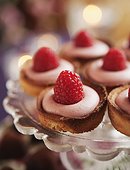 Pastries with raspberries on cake stand, close-up