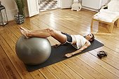Young woman exercising at home with fitness ball