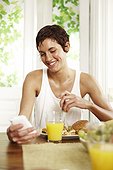 Young woman sitting at breakfast table holding mobile phone