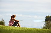 Woman sitting on grass looking at lake