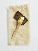 Rye bread and butter knife with butter on paper, studio shot