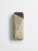 Loaf of dark bread wrapped in paper, studio shot