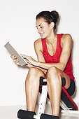 Woman in workout clothes with digital tablet on white background