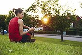 Woman in workout clothes sitting in the grass with mobile phone