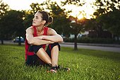 Woman in workout clothes sitting in the grass
