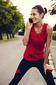 Woman in workout clothes stretching and talking on mobile phone