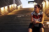 Woman in workout clothes sitting on cement stairs
