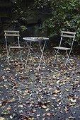 Empty chairs and table in autumn garden