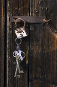 Close-up of barn door with padlock and bunch of keys hanging