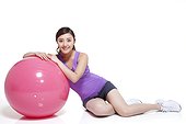 Young woman leaning on a fitness ball