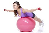 Young woman balancing on a fitness ball with dumbbells
