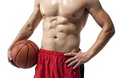Torso of a shirtless muscular man holding a basketball