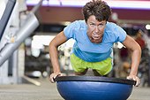 Woman doing Push-ups with Balance Ball in Gym
