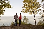 Backview of Young Couple Standing at Edge of Cliff Looking out at View, Ontario, Canada