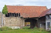 Old stone barn with broken corrugated roof in Hesse, Germany