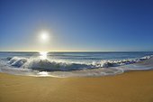 Waves breaking on the shoreline of Ninety Mile Beach at Paradise Beach with the sun shining over the ocean in Victoria, Australia