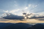 Overview of the silhouetted Vosges Mountains at sunset with sun breaking though the clouds at Le Markstein in Haut-Rhin, France