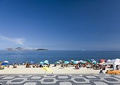 Brazil, Rio de Janeiro, tourists and umbrellas on Panema Beach with sidewalk in foreground