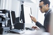 Mid adult man using phone and computer in office