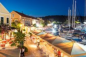 High angle view of people eating out in the harbour of Fiskardo in a summer evening. Kefalonia, Greek Islands, Greece