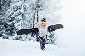 young woman withs snowboard, on winter holiday in Switzerland, walking up the slope