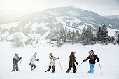 line of young people on winter holiday in switzerland, trekking in the snow