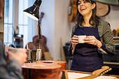 Smiling female worker with coffee cup at guitar workshop