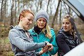 Female friends checking time before jogging in forest