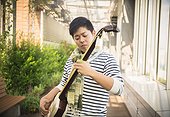 Asian male playing the shamisen