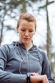 Determined woman checking time before jogging in forest
